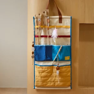 This wall-mounted storage organizer features multiple pockets and elastic straps for holding pet toys, leashes, or other accessories. Its vibrant colors and practical design make it a stylish and functional addition to any space.