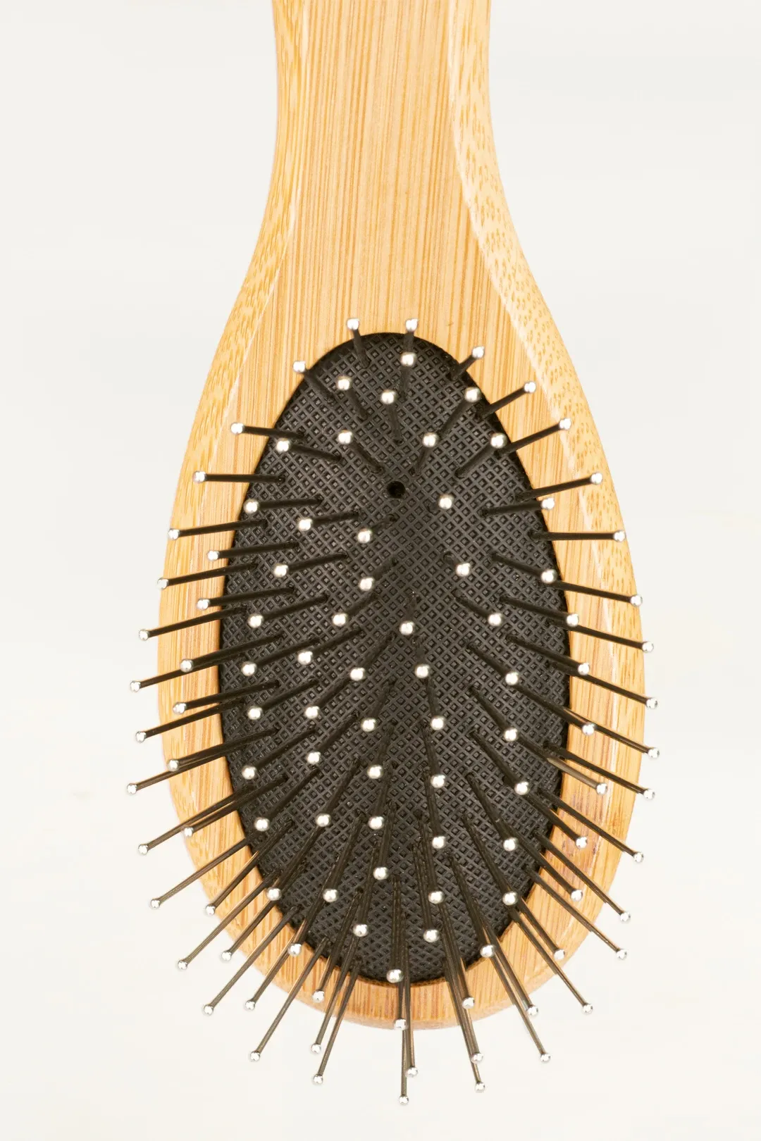 This vertical, top-down shot provides a full view of the bamboo pin brush for dogs against a stark white background. The focus is on the tool's complete silhouette, from the tip of the handle to the oval head packed with pins, highlighting its simple yet functional design.