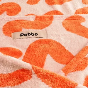 This close-up showcases the "Pebbo" brand label stitched onto the plush, orange and white Dog dry towel, signifying quality craftsmanship. The detailed view reveals the towel's soft, absorbent microfiber texture and the clean stitching of the tag, ensuring durability and a touch of designer style.