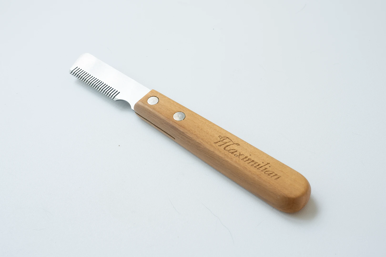 This image displays our expertly crafted Dog hand stripping knife, an essential tool for maintaining the coat of wiry breeds. The comfortable wooden handle provides excellent control, while the specialized blade is designed to grip and remove dead outer hair, preserving the coat's natural texture.