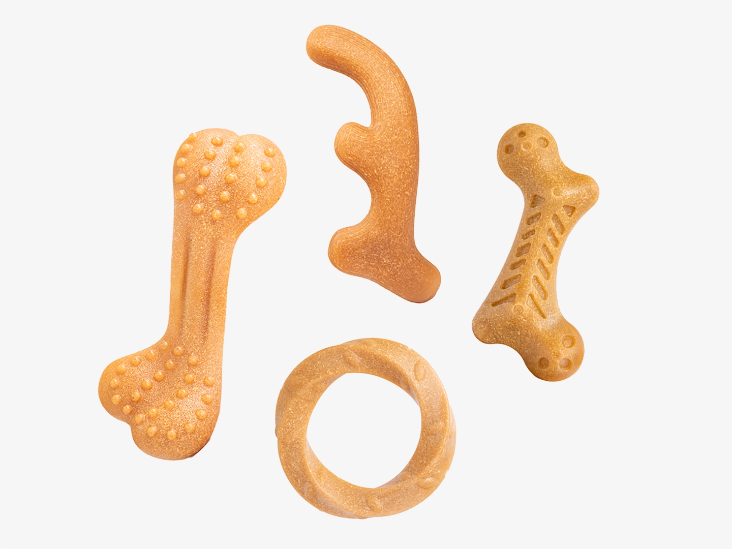 A flat lay of four distinct wooden dog chew toy designs made from a wood composite material. The collection features a large bone with dental nubs, a smooth antler shape, a smaller bone with spine-like textures, and a twisted circular ring for varied chewing experiences.